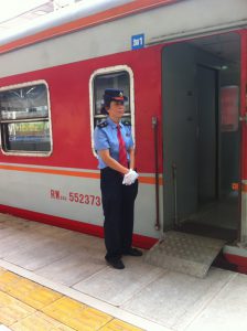Le chef de wagon accueille les passagers sur le quai de la gare de Kunming