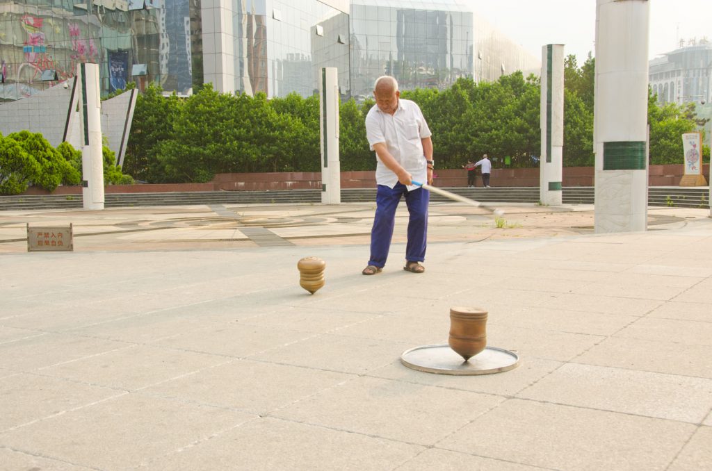 Une toupie chinoise de deux kilos tourne sur un plateau en métal, dans Jiaxiu Square, Guiyang.