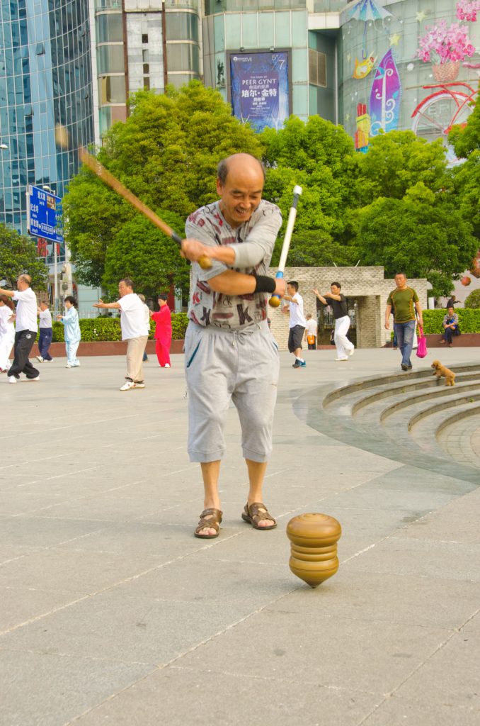 Un joueur de toupie chinoise joue avec deux bâtons dans Jiaxiu Square, Guiyang